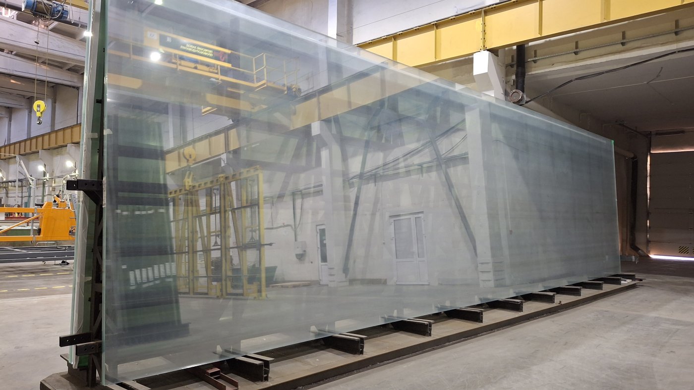 Oversize glass panes standing in a transport rack under a workshop gantry