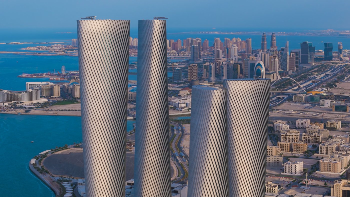 Four towers in Qatar. About 1.1 kilometres of façade between them, built in untreated marine-grade aluminium because the programme would not allow anything else.