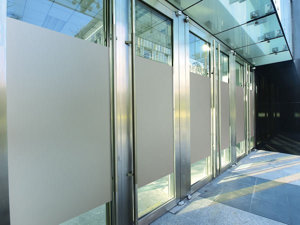 Roughen it and the beam scatters. Sand blasted or diffusing glass reduces specularity rather than reflectance, which is the property that actually causes the complaint.