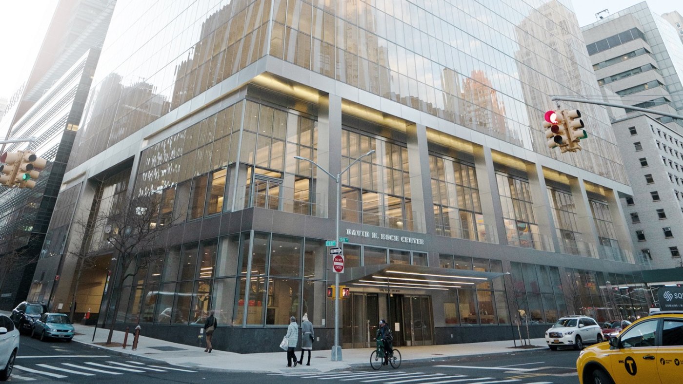 Diffuse against specular. The glass above reflects the building opposite sharply; the stainless below mixes it into a consistent, silky metallic surface.
