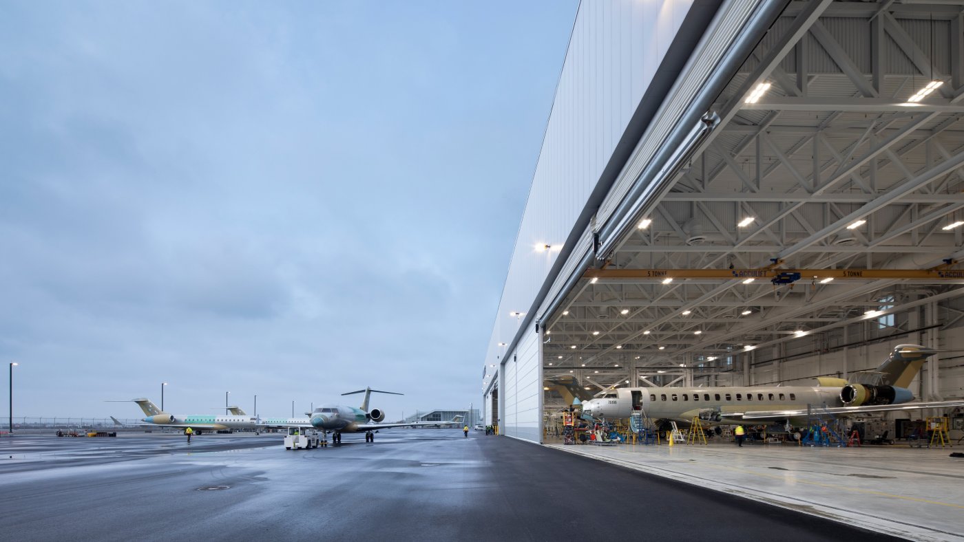 Seventy-five metres clear. The largest aviation doors are hung with translucent fabric and span 75 metres; on the south elevation the doors are more than 55 per cent of the façade.