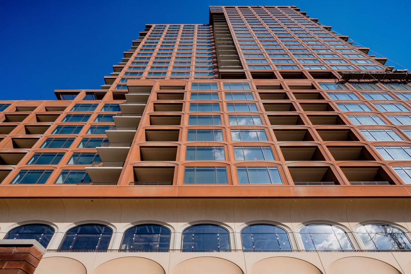 Cream below, red above. Brown described cream precast at the ground, plaster vaults at the recessed second floor, and a reddish brown precast tower.