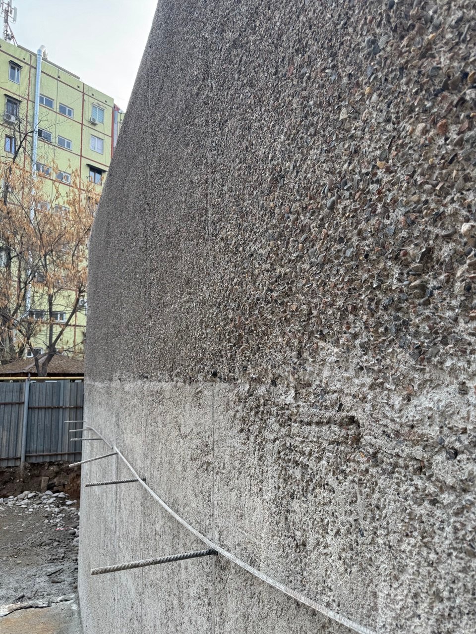 A curved in-situ concrete wall with its aggregate exposed at the surface