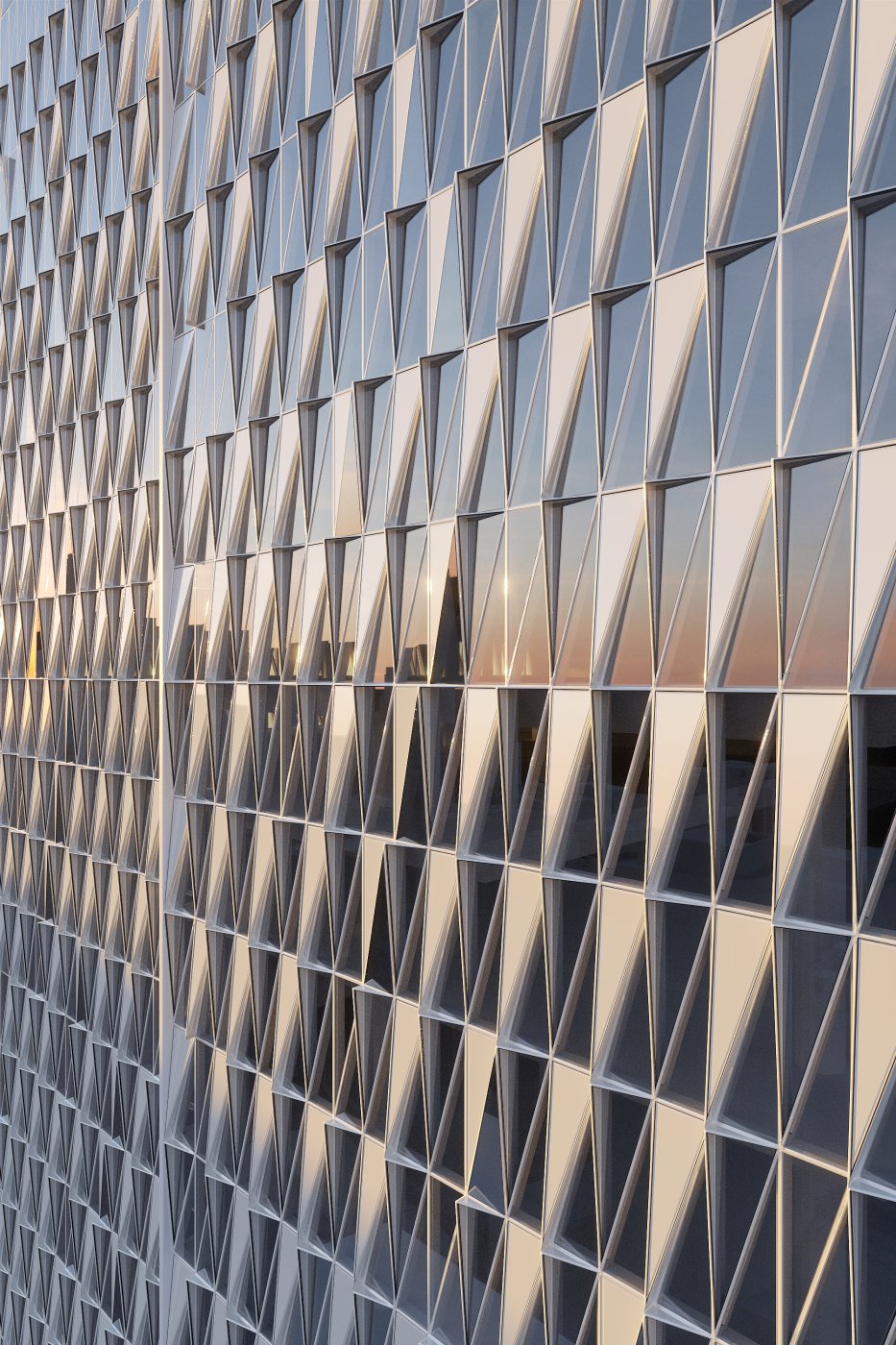 Sixteen per cent, passively. A standard 1,500 by 3,850 module broken four ways: the angled glass and angled panels shade one another, and on one elevation they are mirrored two ways to follow the sun’s rotation.