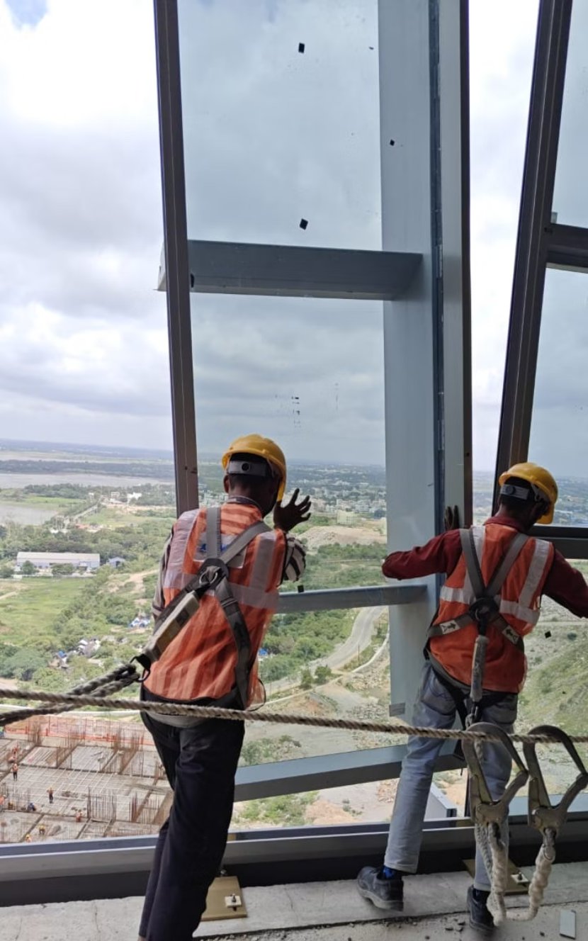 Workers on a catwalk between the two glass skins of a façade, looking out