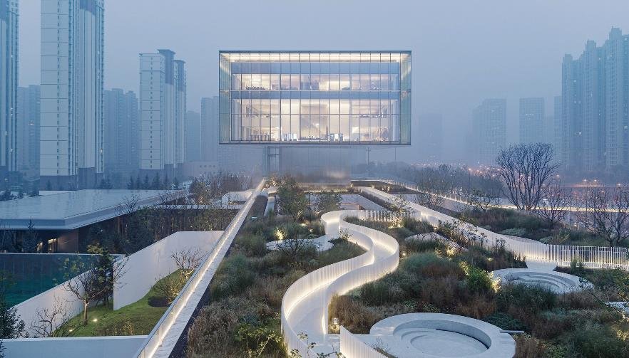 A finish that waits for the weather. The foggy mirror reads as an ordinary panel most of the year and, in the fogs of late autumn and winter, makes the building appear to float.