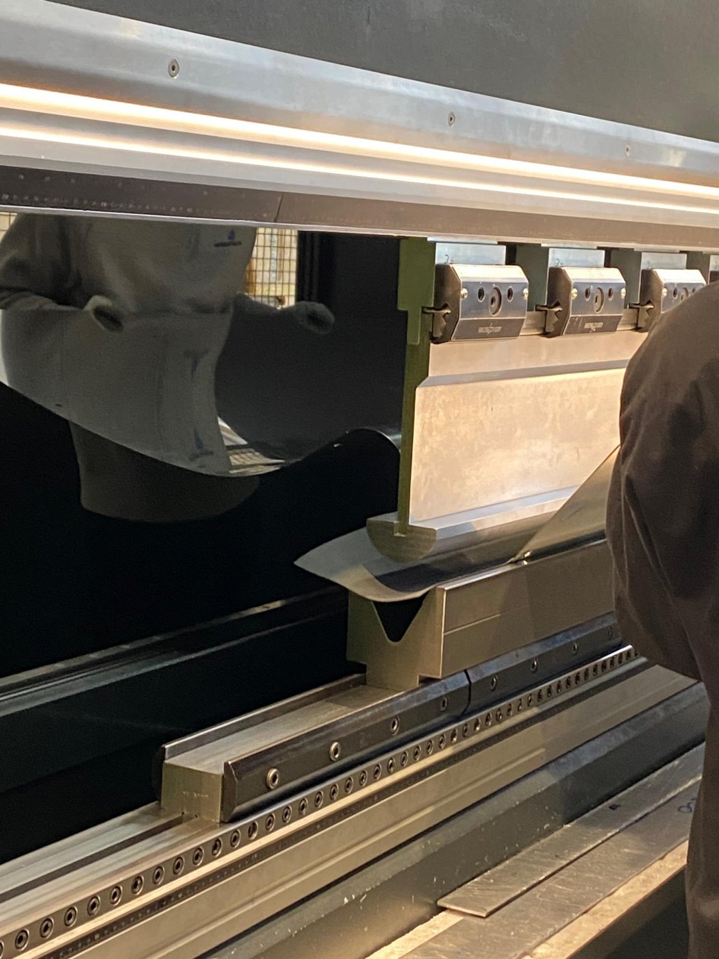 Hand-bent to the model. Every one of the 7,500 panels is bent by hand in Italy, while the profile ribs behind them are CNC-cut from the same 3D model.